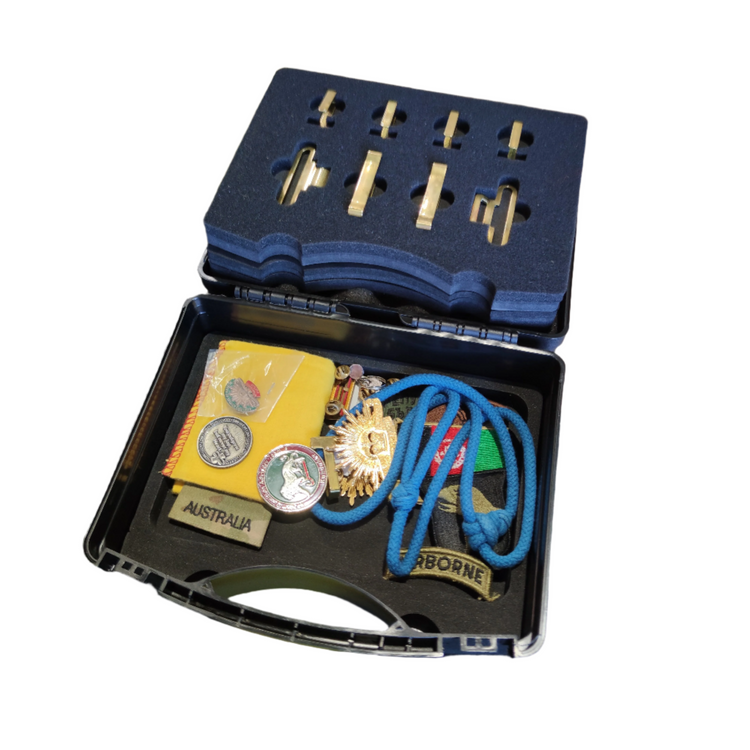 Collection of military insignia and ribbons in a display case on a white background