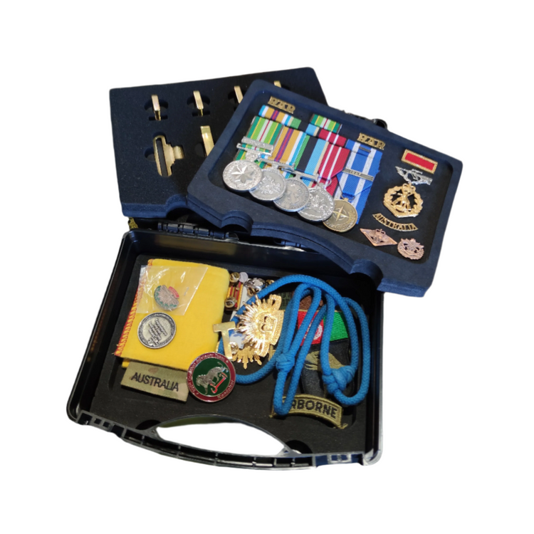Collection of medals, ribbons, and other military memorabilia in an open display case.