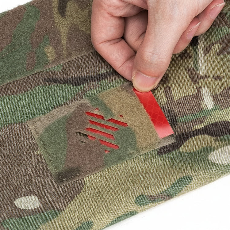 Person applying a red patch to camouflage fabric.
