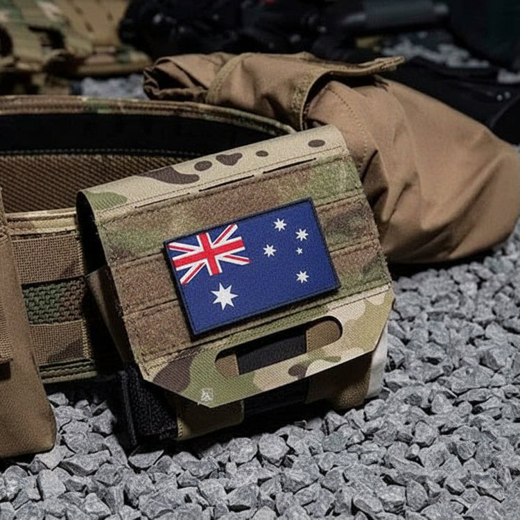 Camouflage tactical vest with American flag patch on a rocky surface