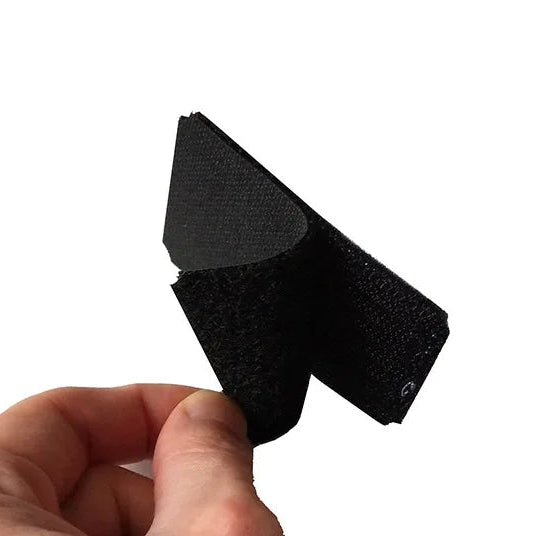 Black velcro strap held by a hand on a white background