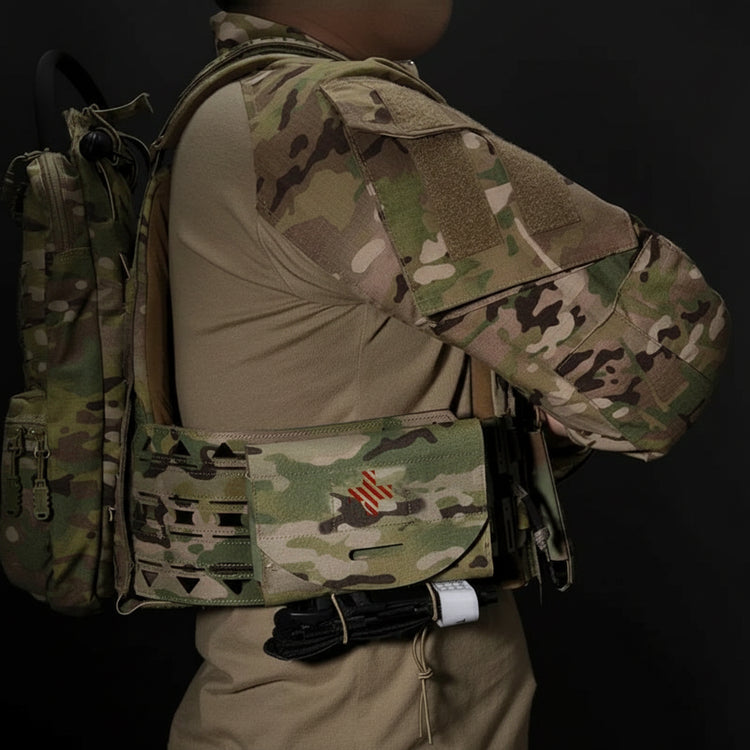 Person wearing a camouflage tactical vest with a backpack showing the first aid pouch on gear on a black background