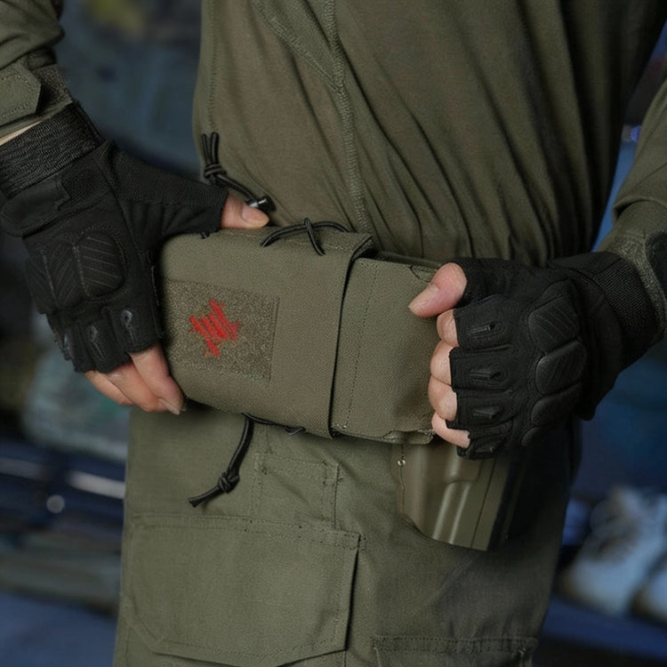 Person holding a green tactical pouch with a red cross, wearing black gloves and green military-style clothing.