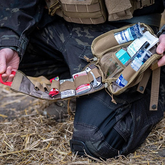 Person holding a tactical pouch with medical supplies on a natural background