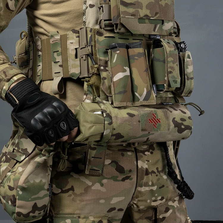 Person wearing a tactical vest with multiple pouches and a gloved hand, on a gray background.