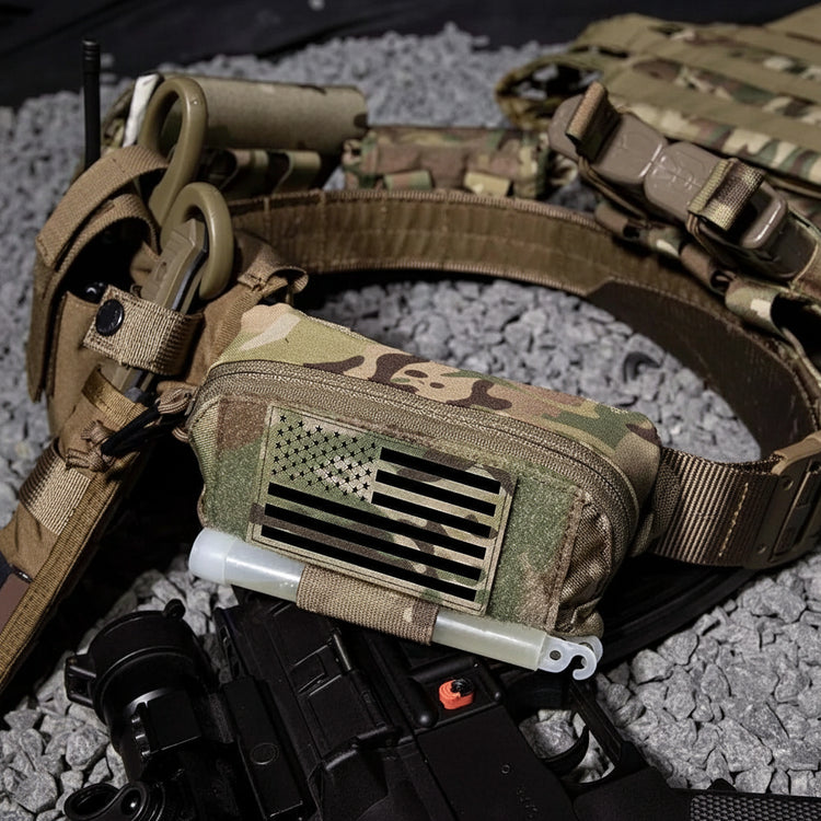 Camouflage tactical belt with pouch and American flag patch on a gravel surface